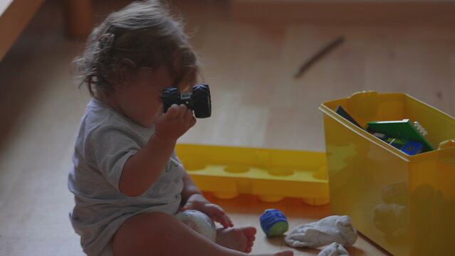 Curly haired toddler crawling on wooden floor at home, playful moment while exploring surroundings and moving towards toys