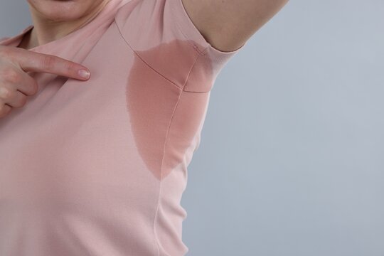Woman with sweaty armpits on light grey background, closeup. Space for text