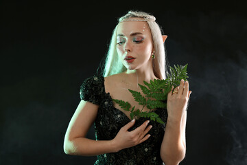 Naklejka premium Beautiful elf girl with floral decor on black background with smoke