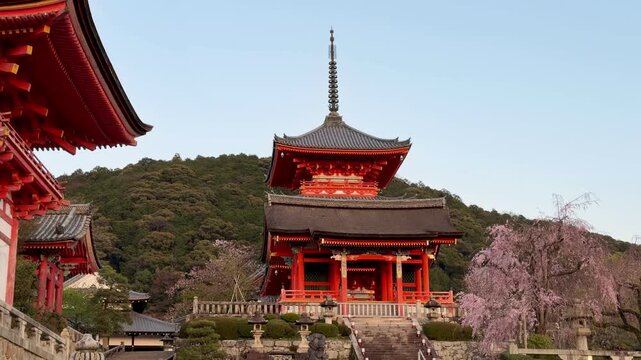 Kyoto, Japan - April 09, 2026: Vibrant orange temple structures and pagoda at the entrance of Kiyomizu-dera in Kyoto, with visitors walking through the historic hillside complex.