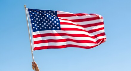 Fototapeta premium American flag waving in the breeze against a clear blue sky