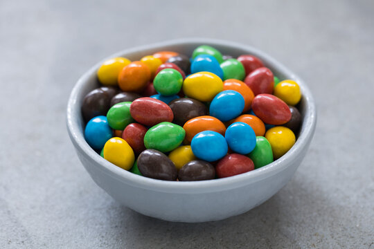 Dragees with peanuts , covered with a crispy multicolored glaze. In a bowl. Light gray background. Close-up	