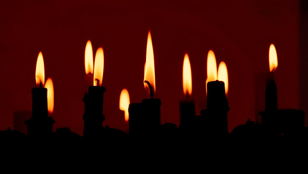 Row of hanukkah candles burning brightly with a dark background.