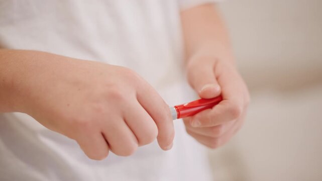 Closeup white childs hands holding marker, uncapping red cap and recapping, gentle finger movements, soft neutral background, casual white shirt, focused preparation for drawing, tactile exploration,