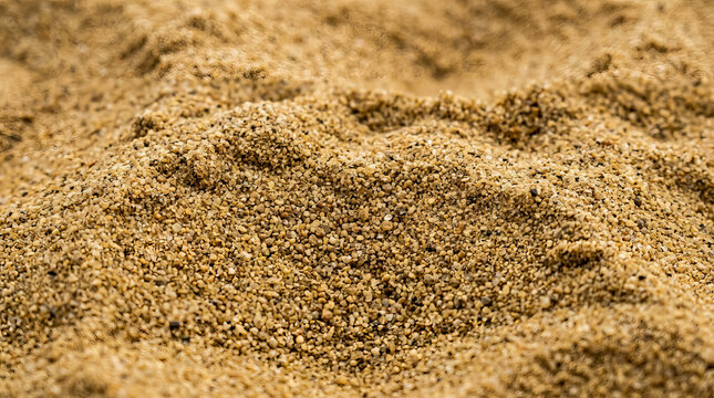 Close up of golden sand grains forming a textured mound under natural lighting, ideal for beach or desert backgrounds.