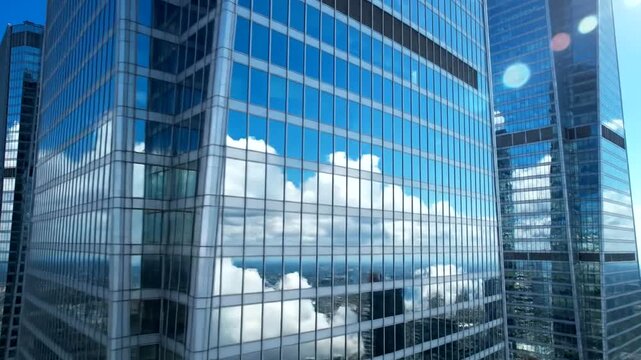Modern Glass Skyscrapers Reflecting Clouds and Blue Sky in a City.