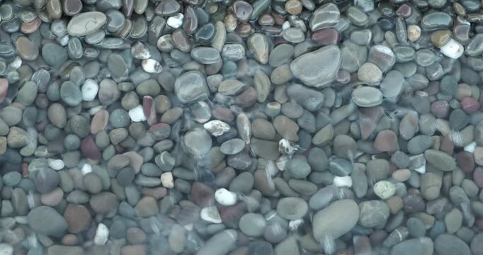 Calm ocean waves idyllic shore beach with turquoise water and pebbles, close-up of sea pebbles with calm sea waves