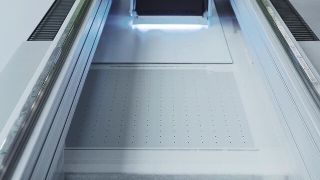 A modern glass printer prints with a large print head.