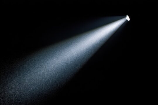 Isolated beam of light from a handheld flashlight against a black backdrop