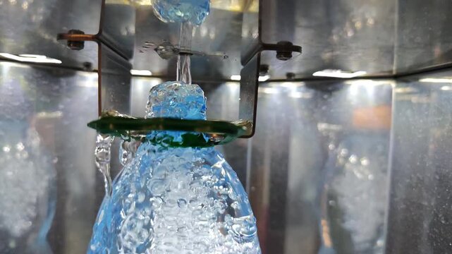 A detailed close-up shot of a clear plastic bottle receiving a rapid flow of fresh, pure drinking water from an automated dispensing machine, highlighting the vigorous bubbling and splashing of the
