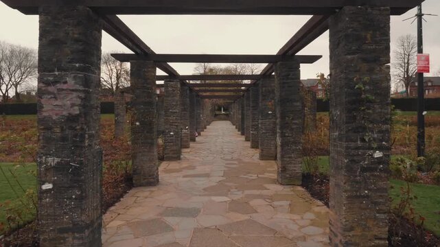 Botanical Garden Stone Pergola Walkway Leading Through Rose Bushes on an Overcast Autumn Day in a Public Park Setting