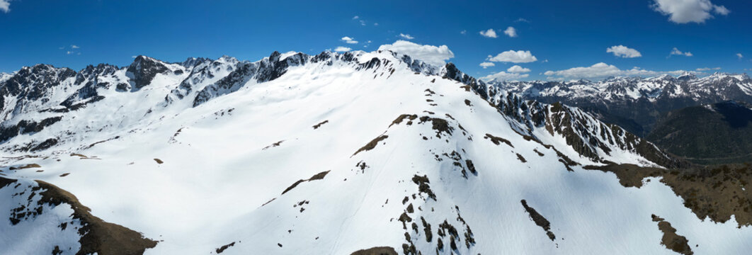 Aerial view of the snow-covered peaks of Pointe Ronde with rocky ridges under a clear blue sky in Trient, Valais, Switzerland.