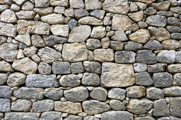 Obraz premium Stone wall texture background. Natural rocks stacked together. Rustic masonry surface pattern. Old building material detail. Gray beige stones pattern. Traditional construction wall design.