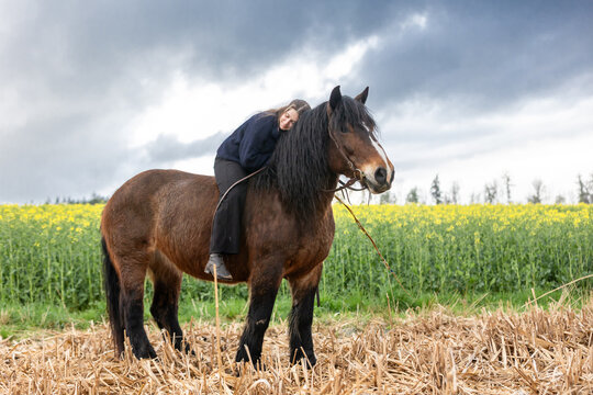 Frau mit Pferd vor Raps und Gewitterwolken