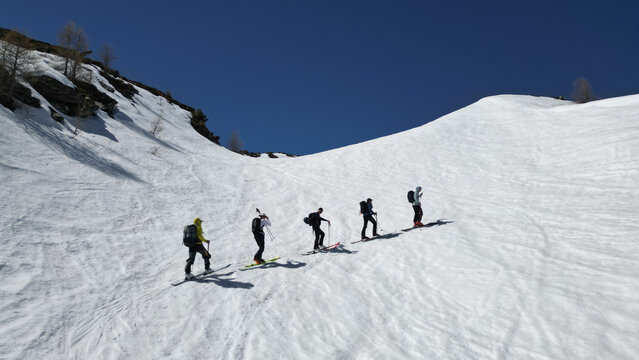 Aerial view of a group of ski tourers climbing the snowy slopes of Pointe Ronde under a clear blue sky in Trient, Valais, Switzerland.