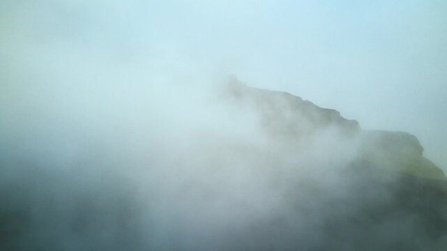 Sea of clouds covering valleys between high altitude mountain peaks in landscape. Natural phenomenon with thick cloud layer blanketing mountainous terrain creating view.