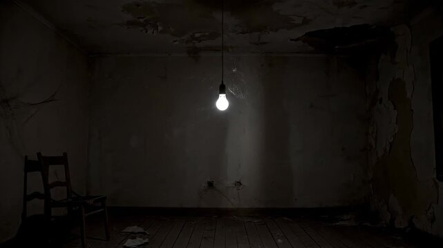 Dim interior of a decaying room with a hanging lightbulb and a lone chair