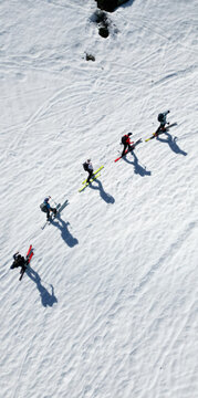 Aerial view of a group of ski tourers ascending the snowy slopes of Pointe Ronde casting long shadows on the textured white snow Trient, Valais, Switzerland.