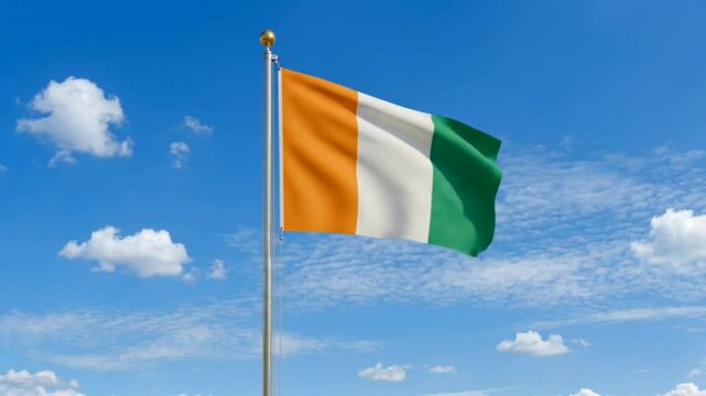 The Ivory Coast flag flies against a bright blue sky.