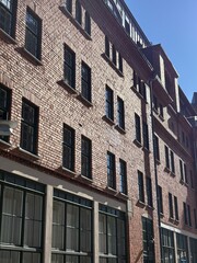 Fototapeta premium Historic Red Brick Building Facade with Black Windows Urban Street