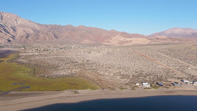 Aerial views show a beautiful sunrise over Bahia De Los Angeles. People camp and explore the beach area as the sun rises.