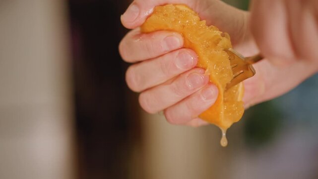 Hands lifting citrus pulp juice. Studio shot capturing hands squeezing orange for fresh juice. Focused studio scene showing hands prying pulp and collecting citrus juice in container