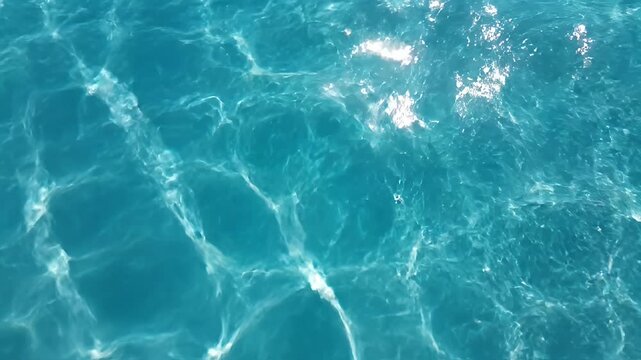 Crystal clear blue water ripples with sunlight reflections