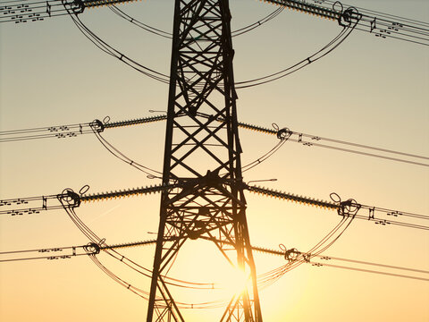 Aerial view of a high-voltage electricity pylon silhouette against a golden sunset sky with intricate power lines in Armthorpe, England, United Kingdom.