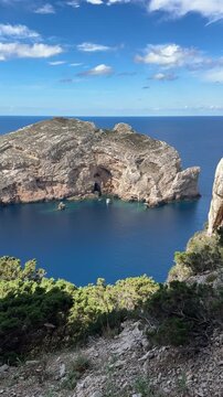 View of Isola di Foradada with its iconic natural arch from the Sardinian mainland at Capo Caccia, Alghero, Italy