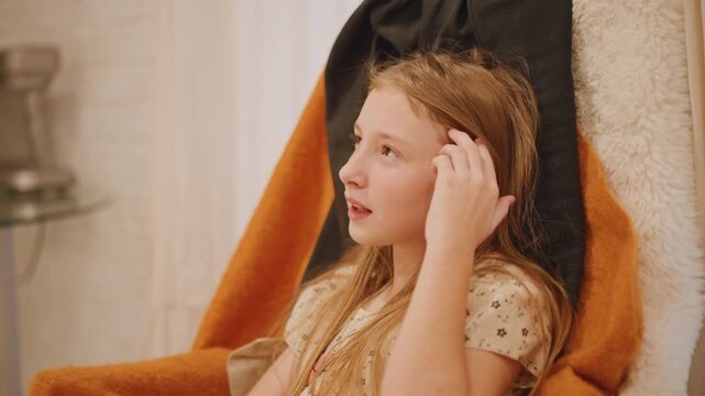 Happy girl with blanket shares joyful moment. Lively girl wearing orange laughs covering mouth brightly. Teenage girl wrapped in orange blankets giggles openly during festive family gathering