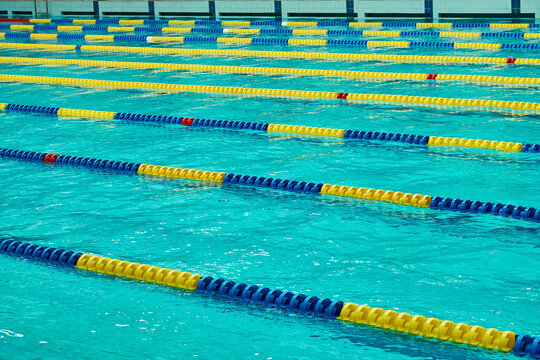 Empty swimming pool with clear blue water and colorful lane dividers. Professional competition lanes in a modern aquatic sports facility