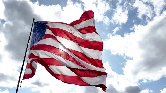 Ascending Drone Shot of American Flag Waving Against Blue Sky and Clouds