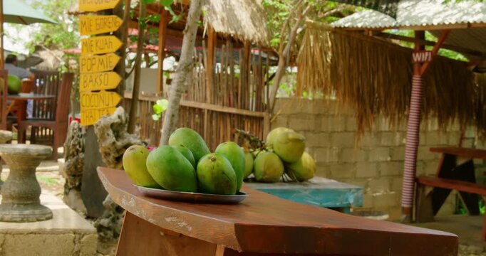 Fresh green mangos and whole coconuts displayed at local tropical roadside food stall in Bali Nusa Penida