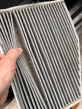Close-up of a dirty cabin air filter covered with dust, dirt, and small debris. Concept of car maintenance, air quality, seasonal replacement, and health concerns such as allergies. Automotive service