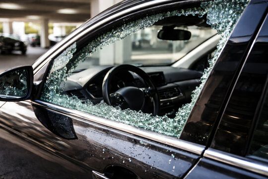 Shattered car window with glass shards in parking area