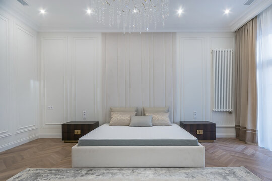 Elegant bedroom interior in neoclassical style. Double bed with pillows, panoramic window.