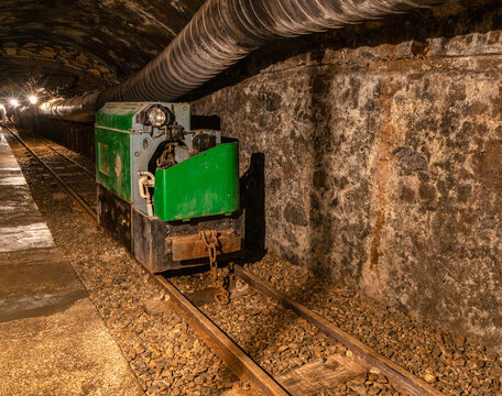 Abandoned mine tunnel with rails and mining cart in an underground environment
