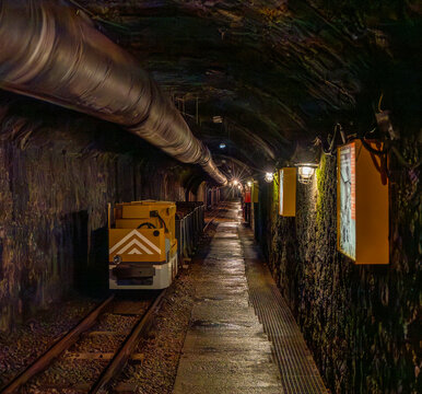 Abandoned mine tunnel with rails and mining cart in an underground environment