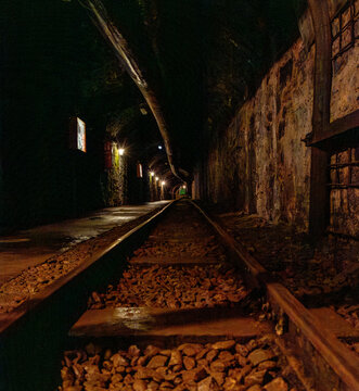 Abandoned mine tunnel with rails and mining cart in an underground environment