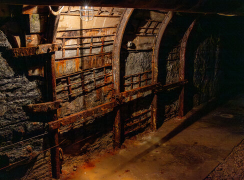 Abandoned mine tunnel with rails and mining cart in an underground environment