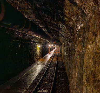 Abandoned mine tunnel with rails and mining cart in an underground environment