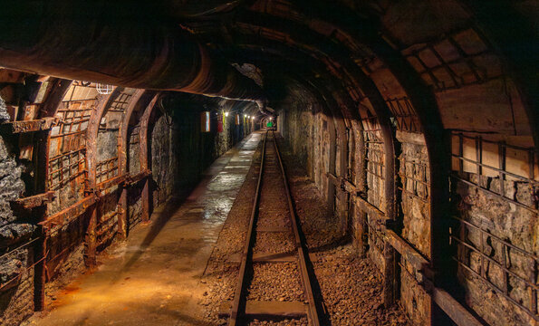 Abandoned mine tunnel with rails and mining cart in an underground environment