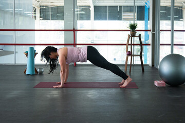Obraz premium Woman exercising plank pose on yoga mat indoors