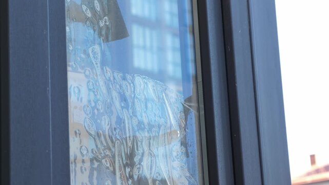 Worker installing and smoothing tint film on window. Man tinting windows with squeegee
