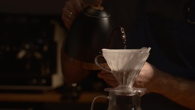 Barista pouring water with gooseneck kettle over V60, precision brewing, slow motion, warm sunlight and deep shadows.