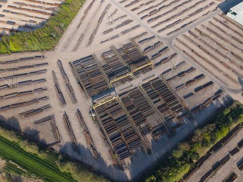 Aerial view of PD Ports showing organized stacks of steel beams and industrial materials with gantry cranes and surrounding greenery in Scunthorpe, England, United Kingdom.