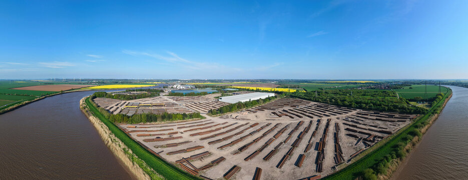 Aerial view of PD Ports industrial storage facility with stacks of materials by the river bend and green fields in Scunthorpe, England, United Kingdom.