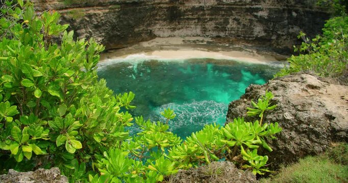 Cliff edge framing beautiful secluded bay with bright turquoise water on sandy beach rock
