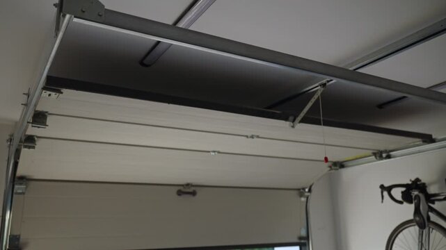 Garage door is closing, viGarage door is closing, view from inside with rails and metal brackets. Home repair, safeew from inside with rails and metal brackets. Home repair, safety and storage concept