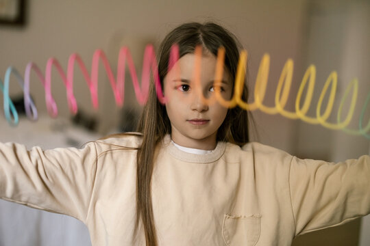 Young girl holds colorful streamers in bright room showing playful energy and cheerful holiday spirit